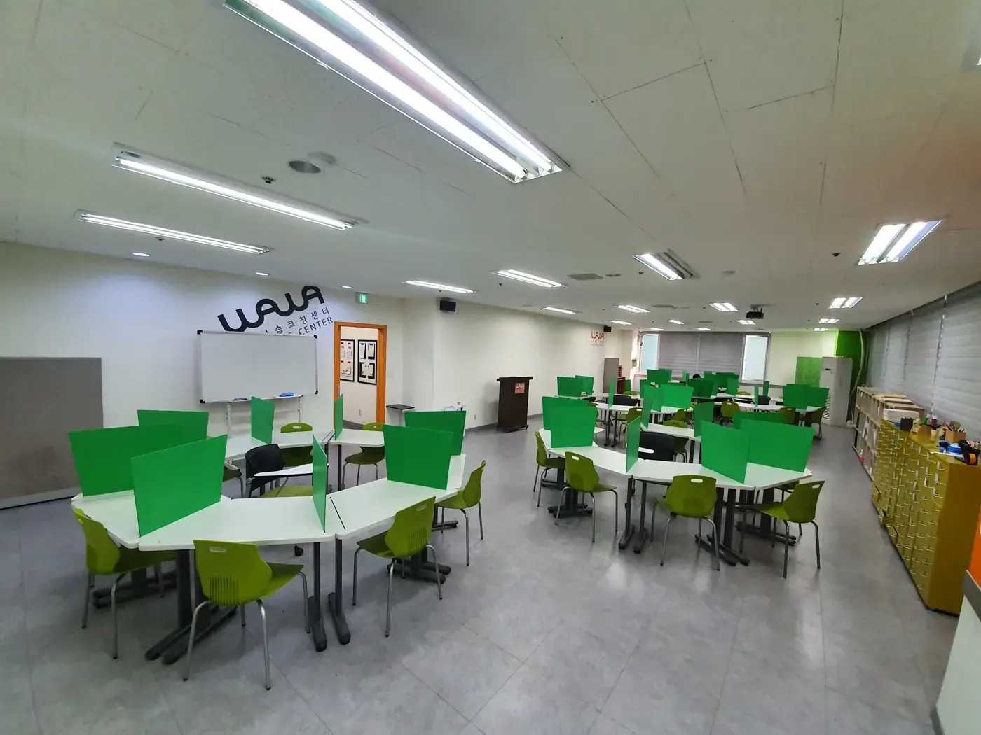 벽면 WAWA 로고 아래 초록 칸막이 모둠 책상이 넓게 펼쳐진 부평점 학습실
