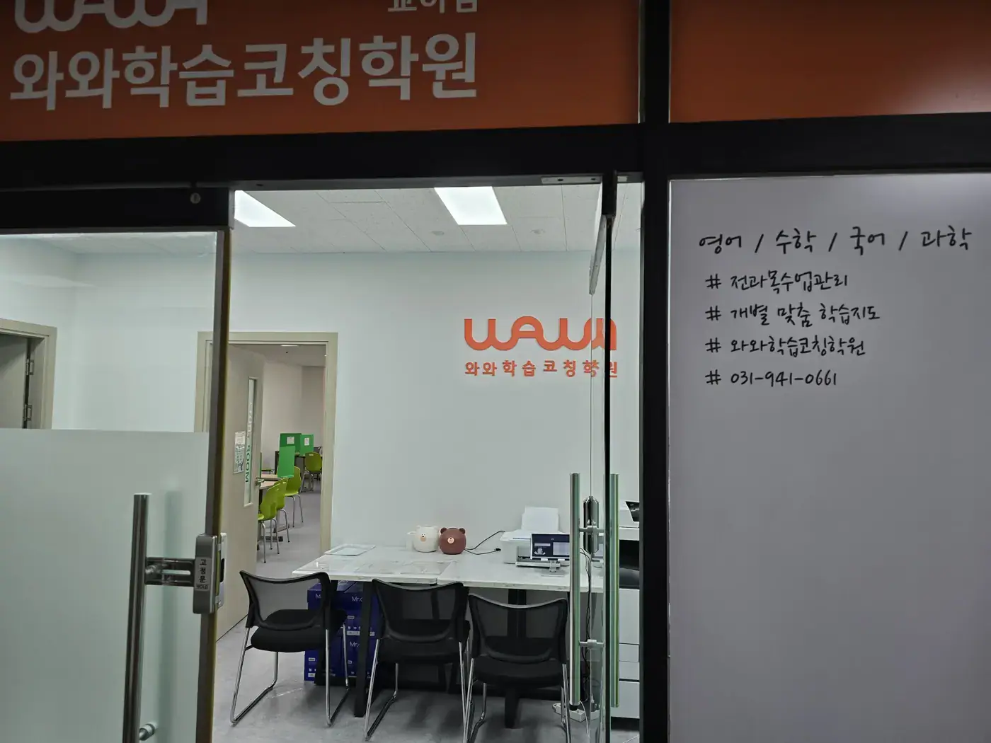 주황색 와와학습코칭학원 간판 아래 유리문 너머로 로고 벽과 상담 테이블이 보이는 교하점 입구