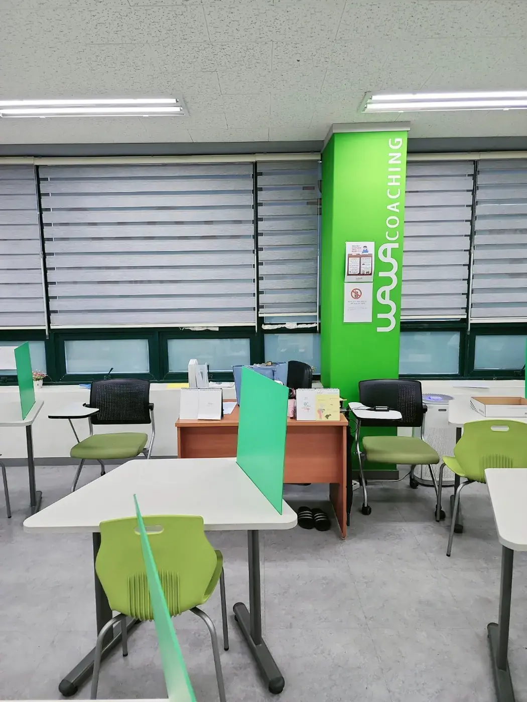 회색 블라인드 창가에 초록색 와와 기둥과 상담 책상이 놓인 이매점 학습 공간